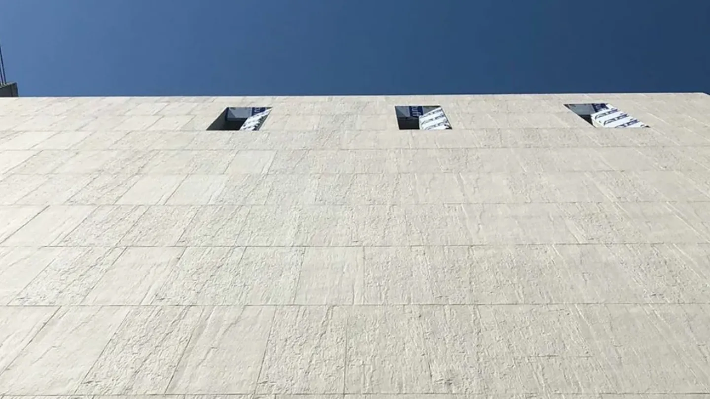 Upward view of a stone-clad commercial facade, a reminder that category decides the checks that matter.