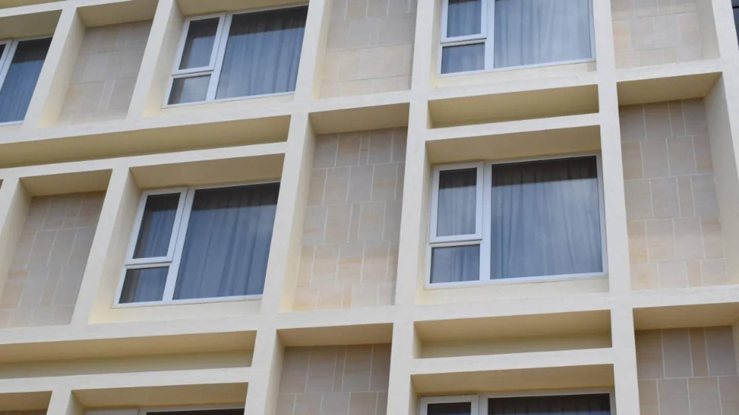 Hotel facade with a deep grid and stone-look infill panels, a cross-border commercial project after goods have cleared.